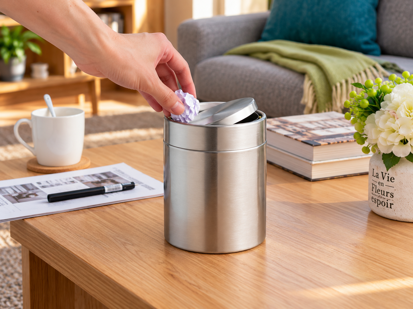EKO Fandy Table Bin – Easy Swing-Lid Waste Disposal Hand disposing of a crumpled paper into the EKO Fandy stainless steel table bin, demonstrating its swing-top lid.