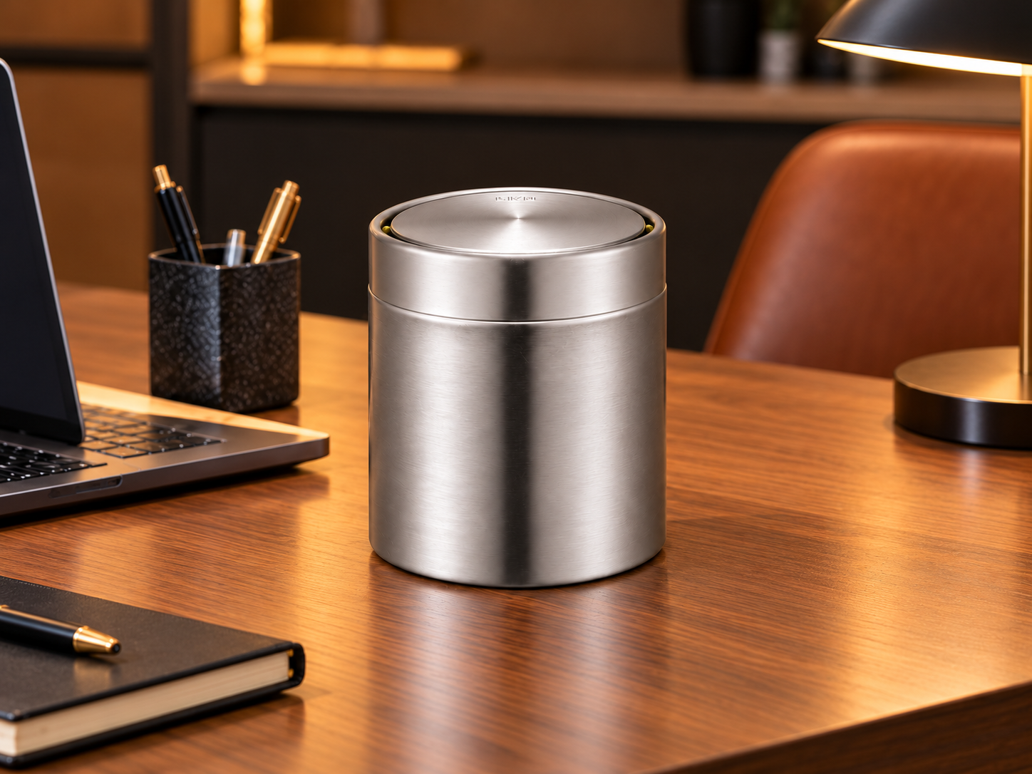 EKO Fandy Mini Swing-Top Bin – Modern Office Desk EKO Fandy tabletop waste bin with brushed stainless-steel finish on a wooden office desk beside a laptop and stationery.